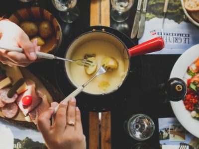 two person holding fork dipping food on sauce